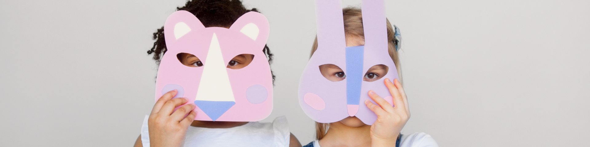 Two Kids Covering Their Faces With a Cutout Animal Mask